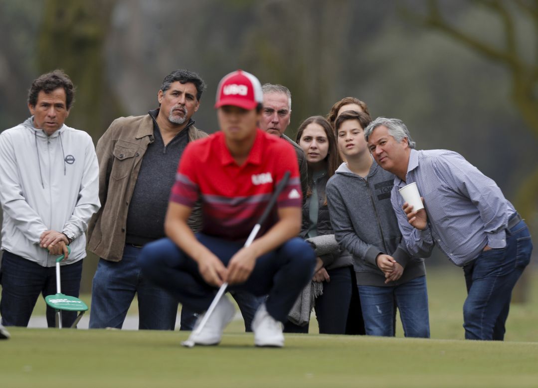 Spectators look on as American golfer Brandon Wu studies his putt on the second hole during the final round of the men's golf competition at the Pan American Games in Lima, Peru, on Sunday, August 11.