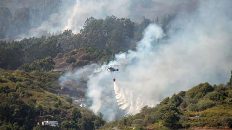 A helicopter drops water over a forest fire raging in the Moya mountains on the island of Gran Canaria on August 19, 2019. 