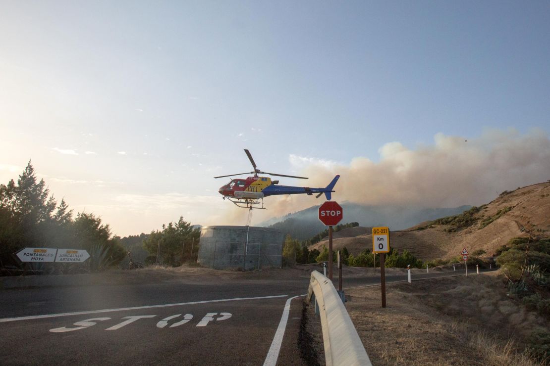 A fire squad helicopter picks up water before dropping it over a forest fire raging in Galdar on the island of Gran Canaria on August 18, 2019. 