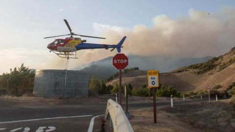 A fire squad helicopter picks up water before dropping it over a forest fire raging in Galdar on the island of Gran Canaria on August 18, 2019. 