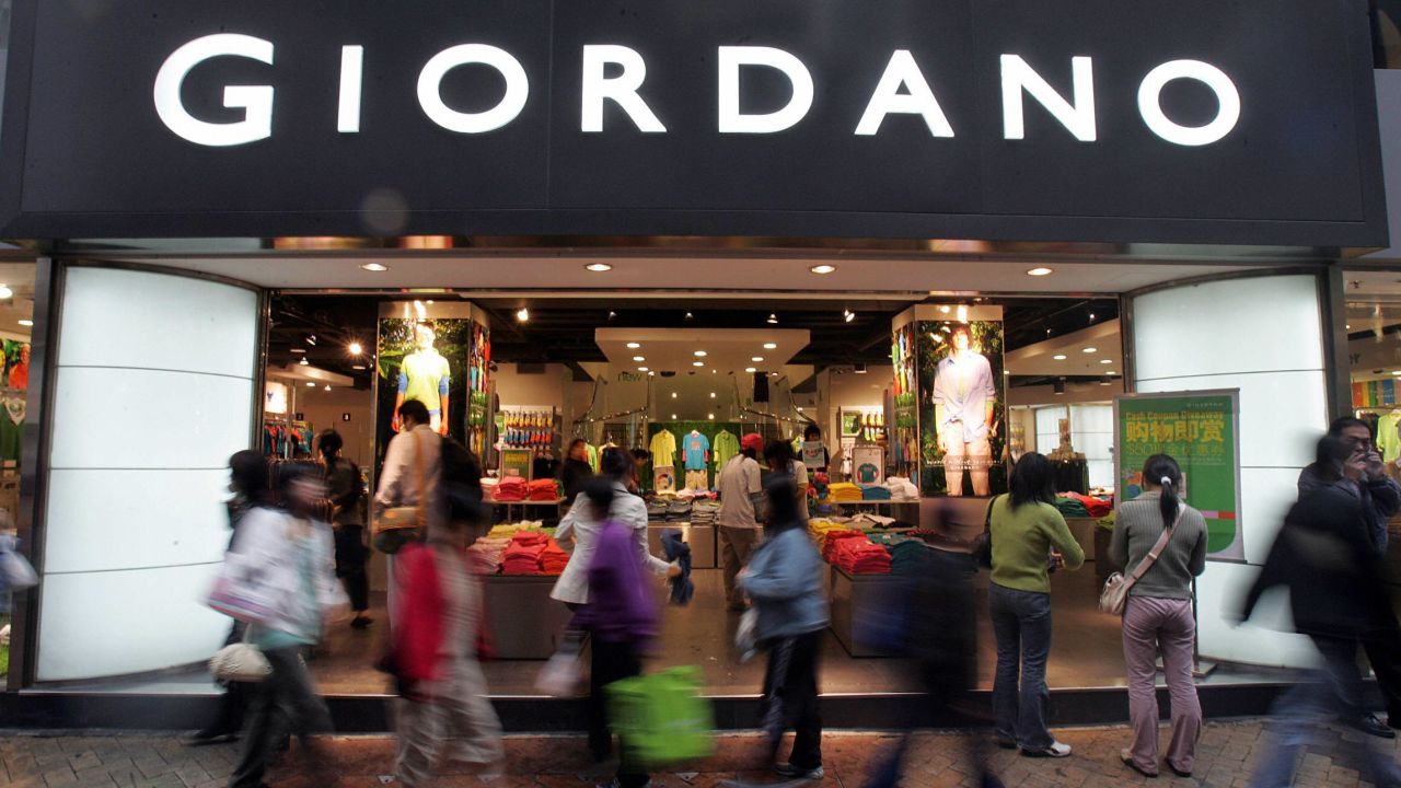 Shoppers pass a Giordano retail store on a rainy day in Hong Kong, 22 March 2005.