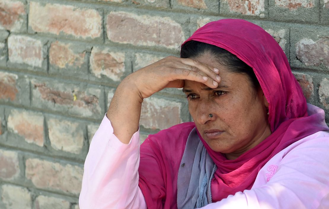An Indian Kashmiri woman waits outside a police station after her relative was detained during night raids in Srinagar on August 20, 2019. 
