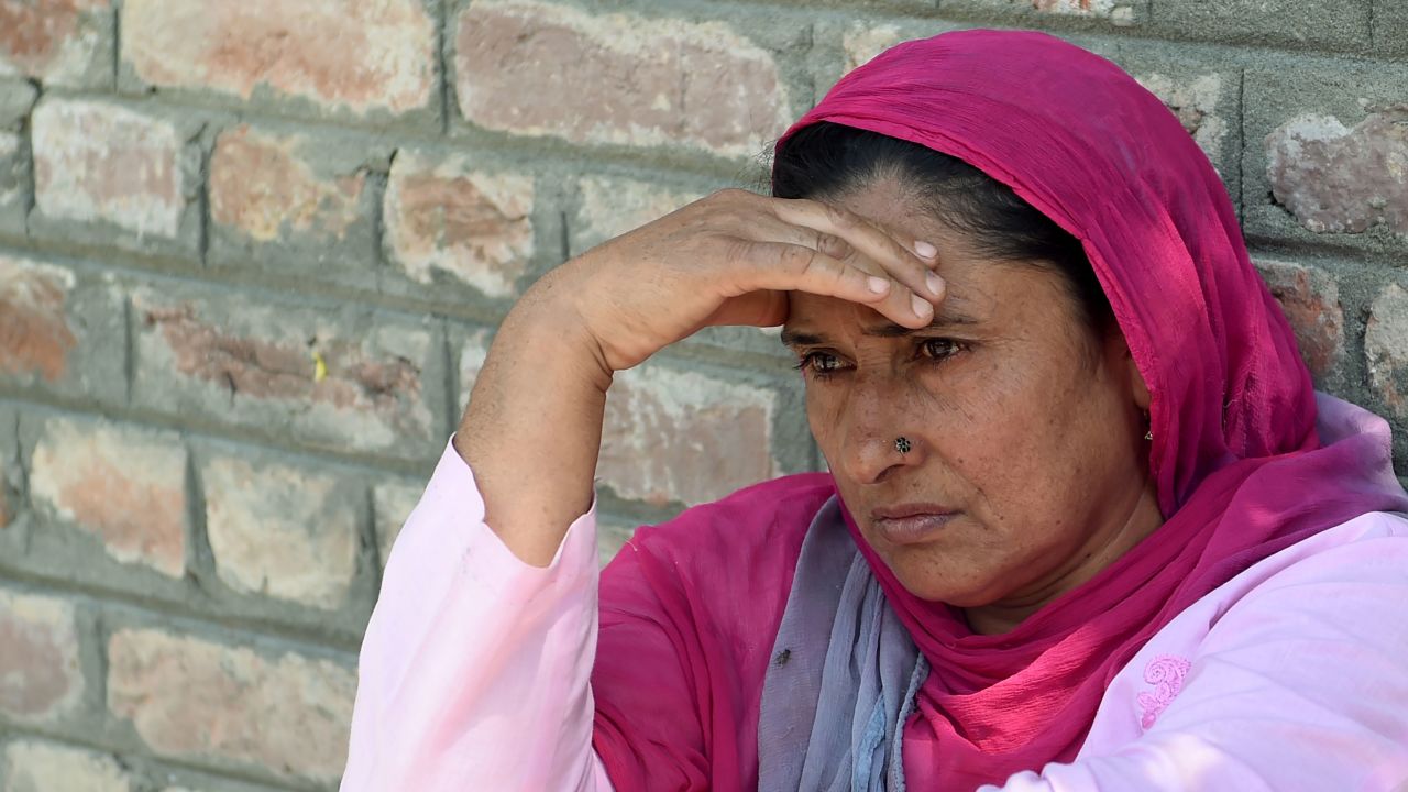 An Indian Kashmiri woman waits outside a police station after her relative was detained during night raids in Srinagar on August 20, 2019.