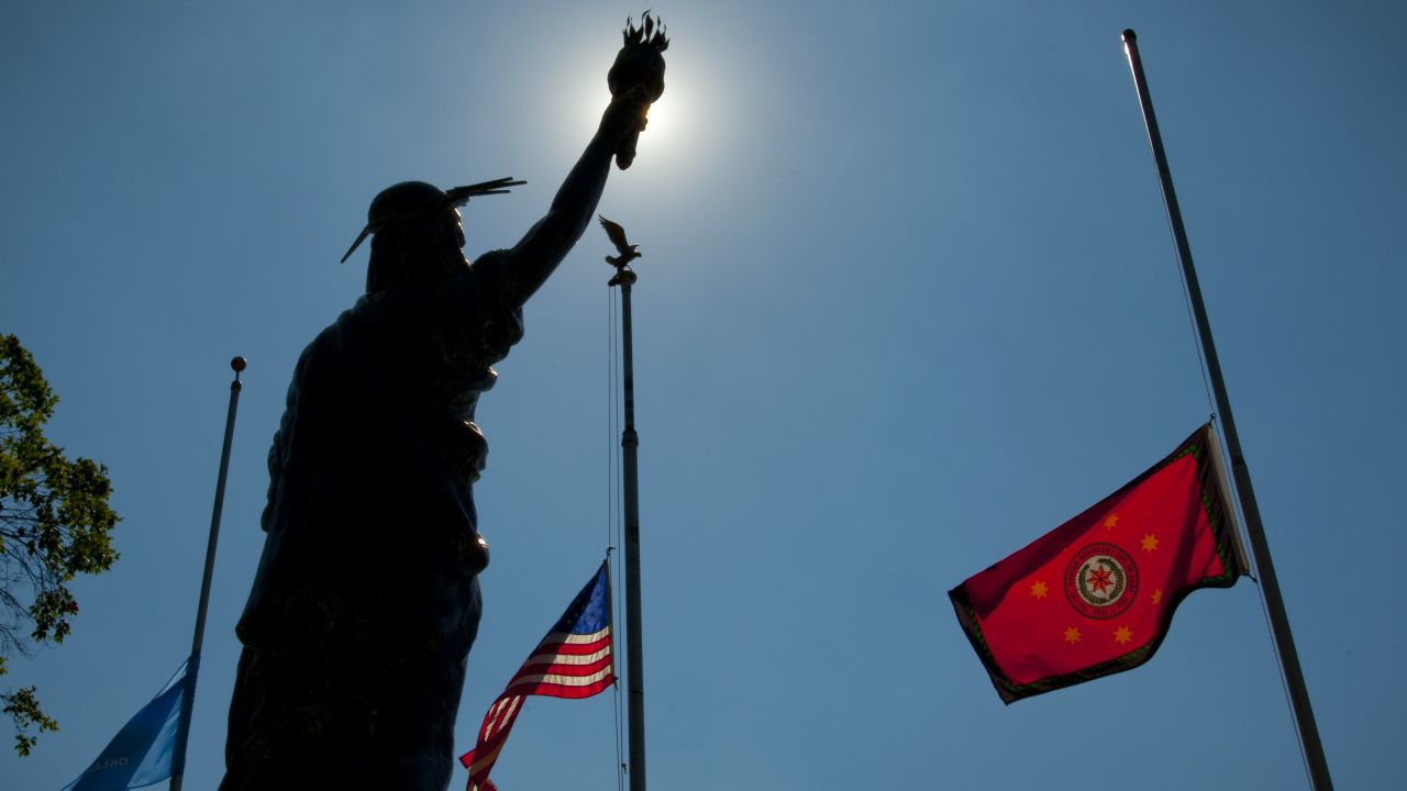 The flags of Oklahoma, the United States and the Cherokee Nation fly behind a sculpture of Lady Liberty at the Cherokee Capitol Square in Tahlequah.