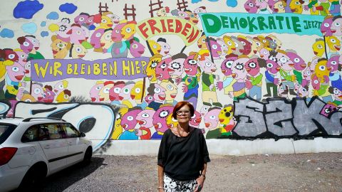 Retired Greens MEP, Gisela Kallenbach, poses in front of a mural depicting the 1989 protests.