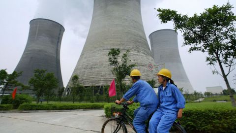 Workers cycle past power stations in Guangan, in southwest China's Sichuan province.