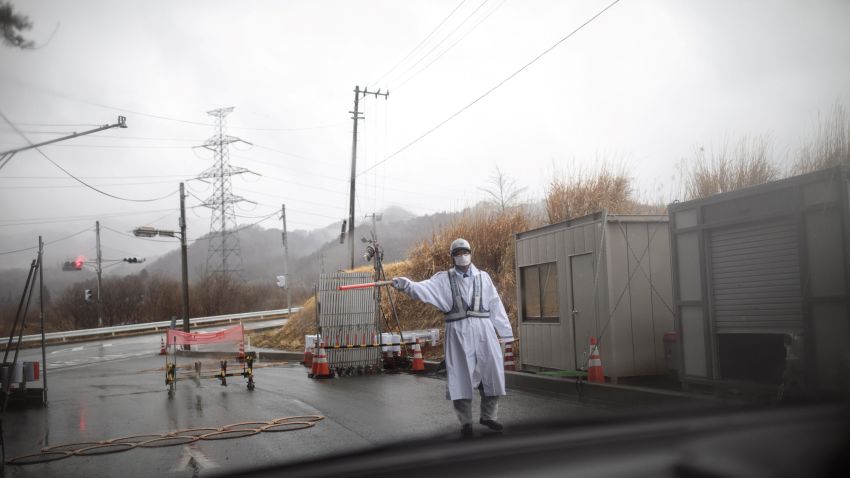 This picture taken on March 5, 2018 shows a guard gesturing at a checkpost exit from the exclusion zone of Futaba town, Fukushima prefecture, as Japan prepares to mark the 7th anniversary of the devastating 2011 earthquake and tsunami that triggered the Fukushima nuclear disaster. - The nuclear accident, following a tsunami and earthquake on March 11, 2011, drove more than 160,000 people from their homes, some by evacuation order and others by choice. Some have since returned but many stayed away, creating a new life elsewhere amid lingering concerns about radiation. (Photo by Behrouz MEHRI / AFP) (Photo credit should read BEHROUZ MEHRI/AFP/Getty Images)