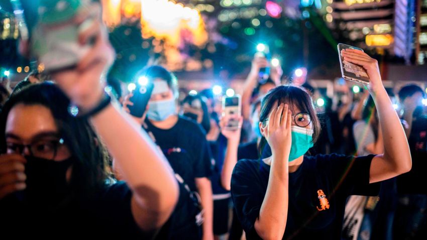 TOPSHOT - Secondary school students cover their right eye as they hold up their phone torches while attending a rally at Edinburgh Place in Hong Kong on August 22, 2019. - Hong Kong student leaders on Thursday announced a two-week boycott of lectures from the upcoming start of term, as they seek to keep protesters on the streets and pressure on the government. (Photo by Anthony WALLACE / AFP)        (Photo credit should read ANTHONY WALLACE/AFP/Getty Images)