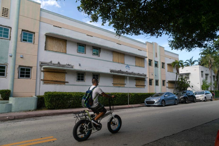 A man rides a bike by a Miami Beach building with boarded-up windows on August 29.