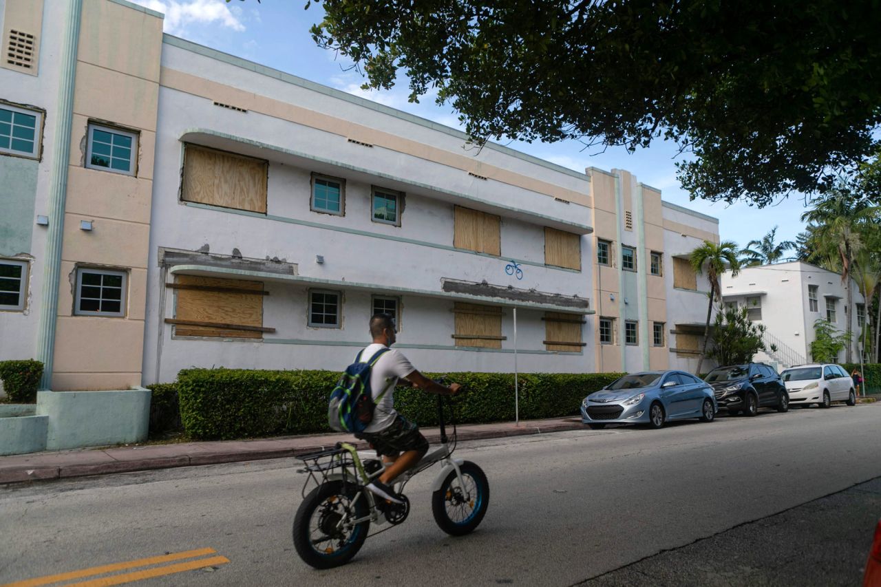 A man rides a bike by a Miami Beach building with boarded-up windows on August 29.