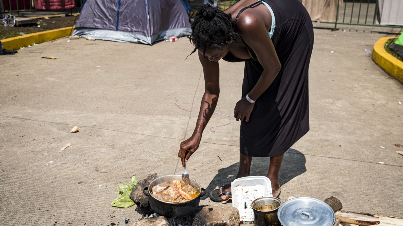 A migrant from Angola who is six months pregnant cooks in the street in front of Siglo XXI immigration facility.
