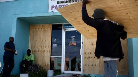 Workers board up a shop's window front as they make preparations for Hurricane Dorian in Freeport, Bahamas.