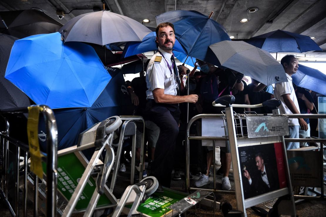 An airline crew member makes his way through a barrier set up by protesters at Hong Kong International Airport on September 1, 2019.