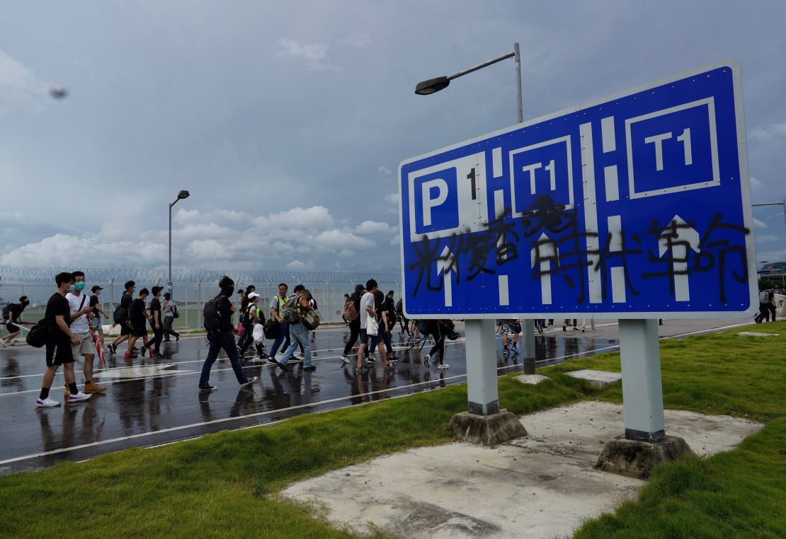 Pro-democracy protestors walk towards the airport past a vandalized signage in Hong Kong, Sunday, Sept.1, 2019. 