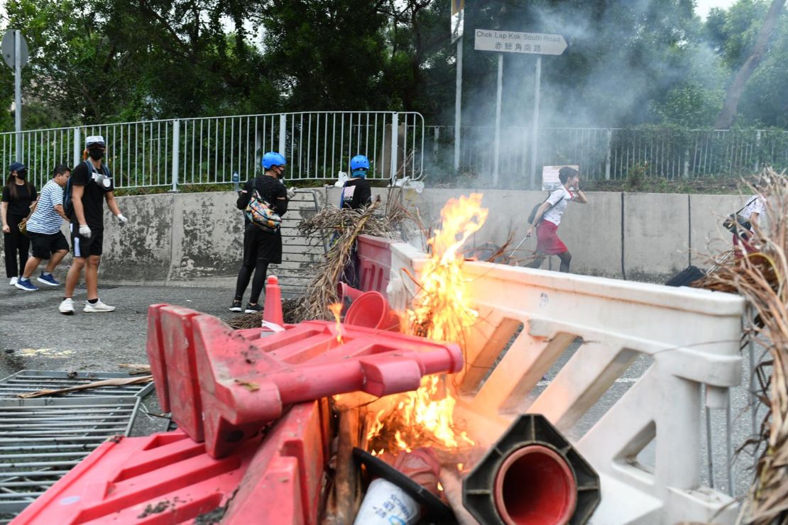 A flight attendant sprints past a burning barricade in Tung Chung on the way to Hong Kong international airport.
