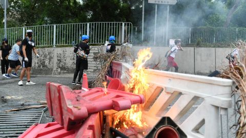 A flight attendant sprints past a burning barricade in Tung Chung on the way to Hong Kong international airport during protests on September 1, 2019.