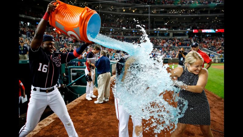 Washington Nationals' Victor Robles, left, douses teammate Anthony Rendon and MASN reporter Alex Chappell after a baseball game against the Miami Marlins in Washington, D.C., on Friday, August 30. The Nationals won 7-6.