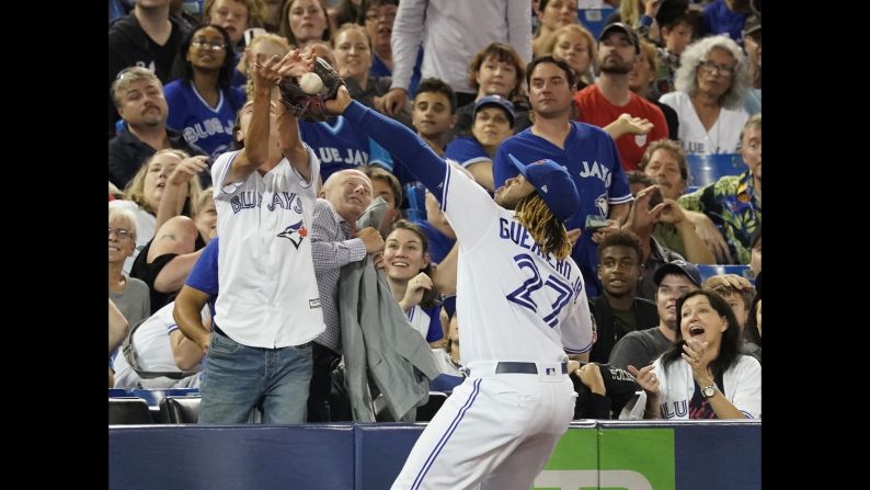 A fan interferes as Toronto Blue Jays third baseman Vladimir Guerrero Jr. tries to catch a pop-fly during the sixth inning at Rogers Centre in Toronto, Canada, on Tuesday, August 27.