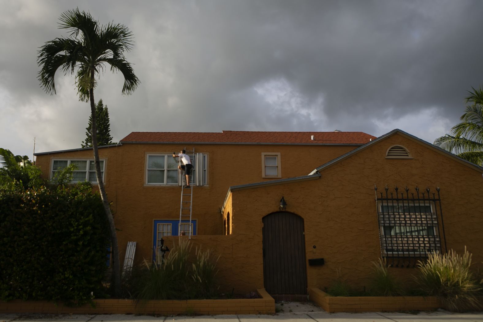 A man places a shutter in a window in Lake Worth, Florida.