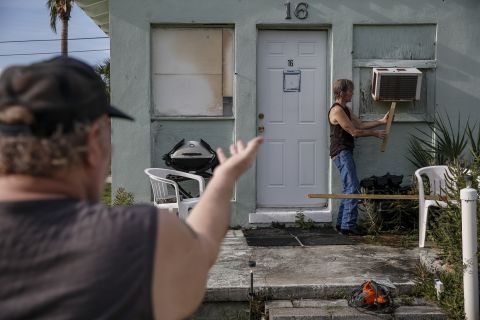 Riverside Mobile Home Park residents Joe Lewis, left, and Rob Chambers work to secure an air conditioner before evacuating the park in Jensen Beach, Florida.