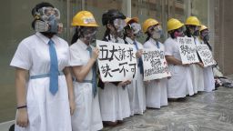 Students wearing gas masks and helmets hold a banner that reads "five major demands are indispensable" at St. Francis' Canossian College in Hong Kong.