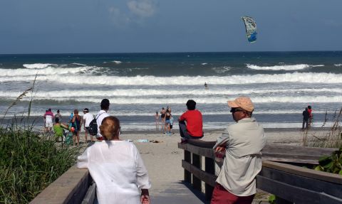 Beachgoers watch a man ride a kiteboard in Indialantic, Florida, on Sunday, September 1.