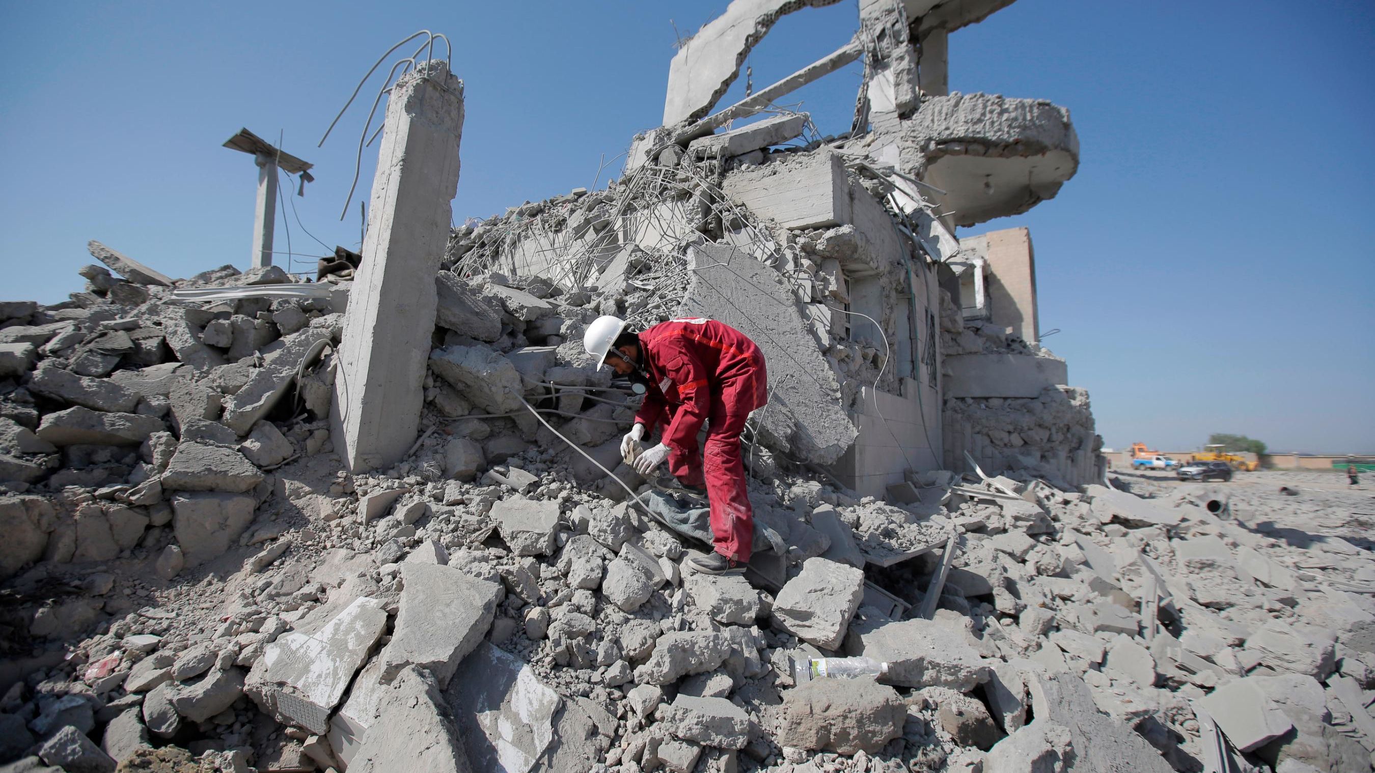 A rescue worker recovers a body from under the rubble of the detention center following the strikes.