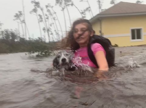 Julia Aylen carries her dog as she wades through waist-deep water near her home in Freeport on September 3.