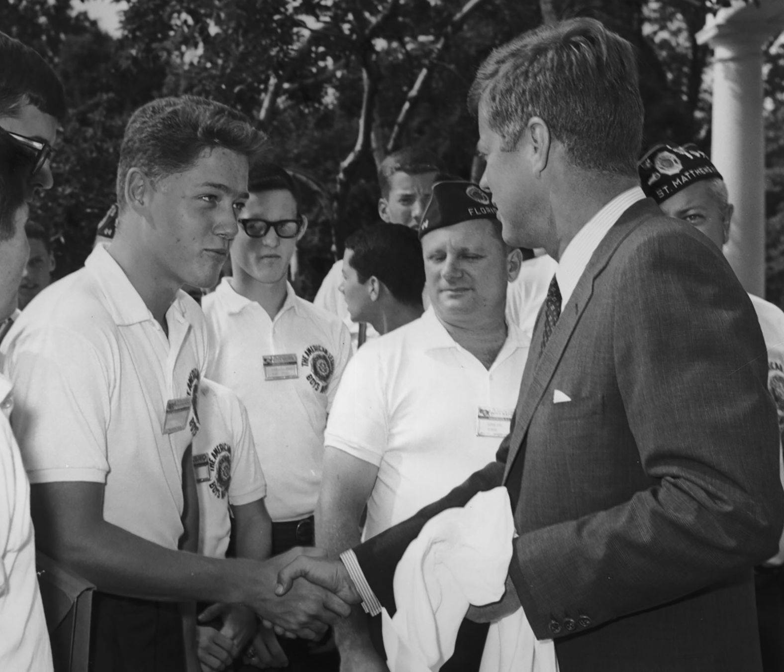 A young Clinton shakes hands with President John F. Kennedy while other American Legion Boys Nation delegates look on during a trip to the White House in 1963.