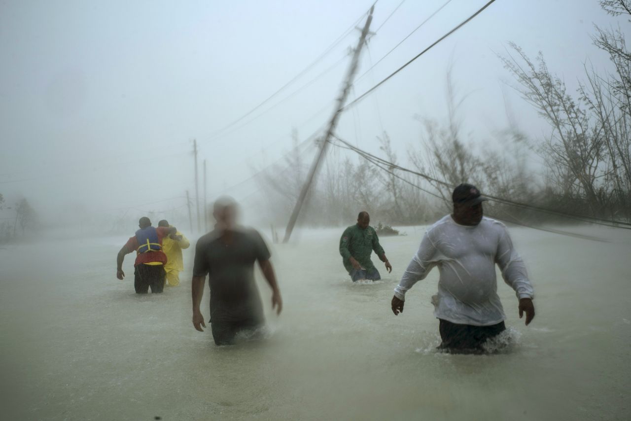 Volunteers walk down a flooded road as they work to rescue families near the Casuarina Bridge in Freeport on September 3.