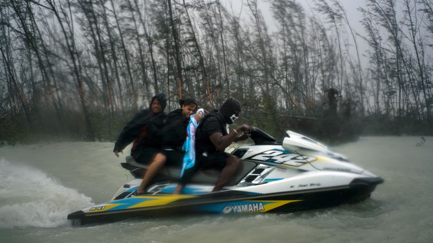 A woman who was trapped by flood waters during Hurricane Dorian is transported out of the area by volunteers on a jet ski near the Causarina bridge in Freeport, Grand Bahama, Bahamas, Tuesday, Sept. 3, 2019. The storm's punishing winds and muddy brown floodwaters devastated thousands of homes, crippled hospitals and trapped people in attics. (AP Photo/Ramon Espinosa)