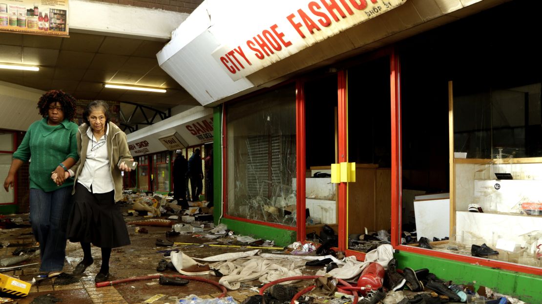 A shoe shop owner is helped by a staff member to inspect the damage caused by looters in Germiston, east of Johannesburg, South Africa.