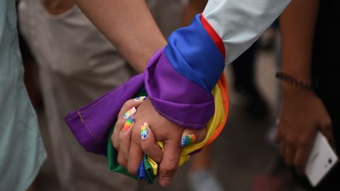 A couple hold hands wrapped in a rainbow flag during a pride march in Marikina City, east of Manila on June 30, 2018. 