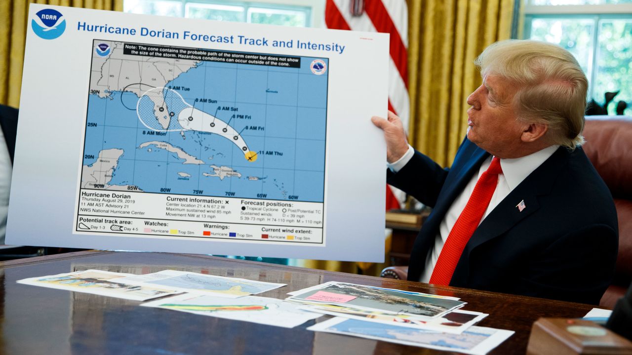 President Donald Trump holds a chart as he talks with reporters after receiving a briefing on Hurricane Dorian in the Oval Office of the White House, Wednesday, September 4, 2019, in Washington.