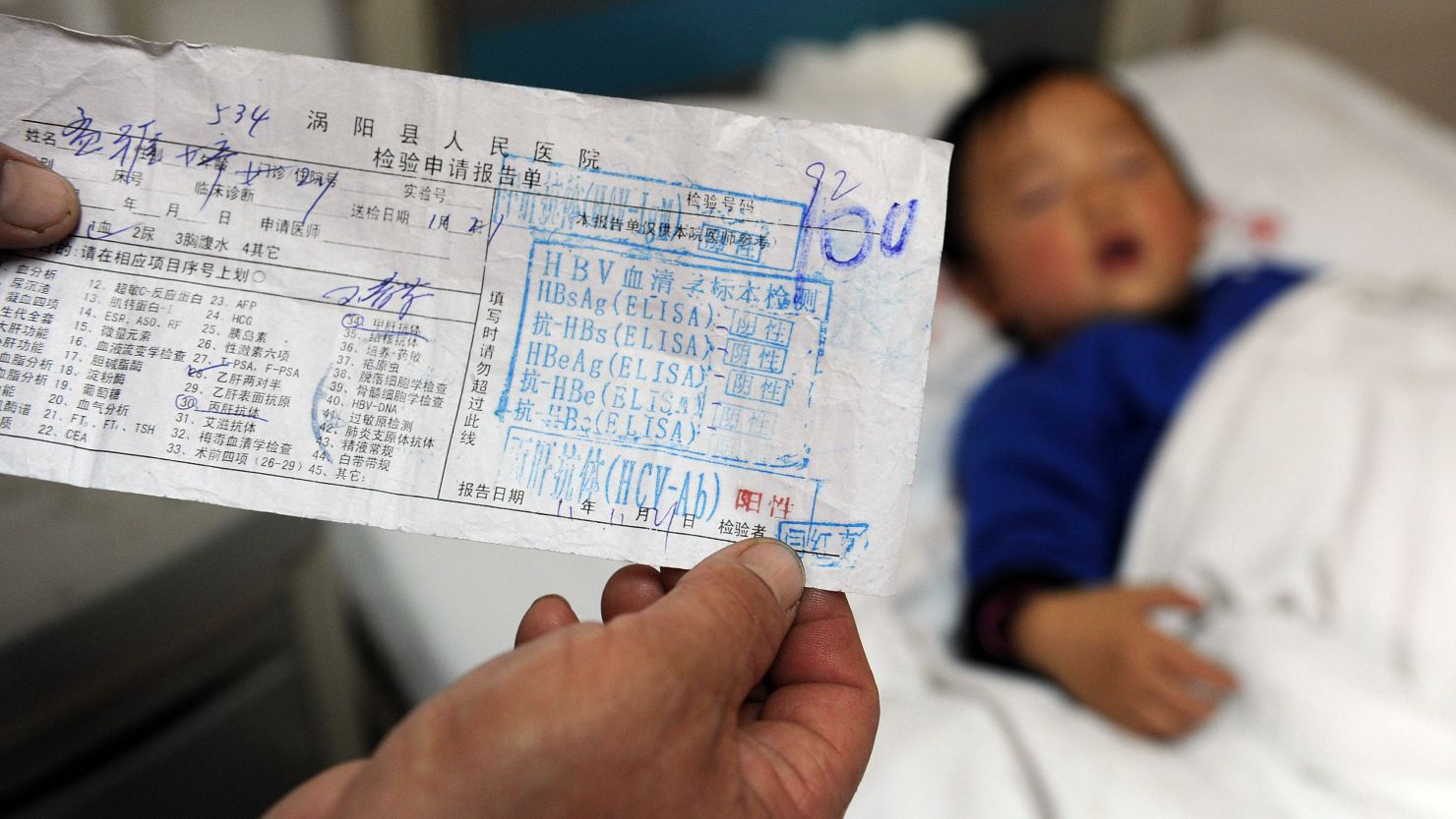 In this picture taken on November 28, 2011, a Chinese parent shows a test result slip confirming his child has hepatitis C, at a hospital in Hefei, east China's Anhui province.