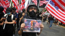 A man holds a placard as protesters wave US national flags while they march from Chater Garden to the US consulate in Hong Kong on September 8, 2019, to call on the US to pressure Beijing to meet their demands and for Congress to pass a recently proposed bill that expresses support for the protest movement. - Pro-democracy activists planned to rally outside the US consulate in Hong Kong on September 8 as the they try to keep international pressure on Beijing following three months of huge, sometimes violent, protests. (Photo by Vivek Prakash / AFP)        (Photo credit should read VIVEK PRAKASH/AFP/Getty Images)
