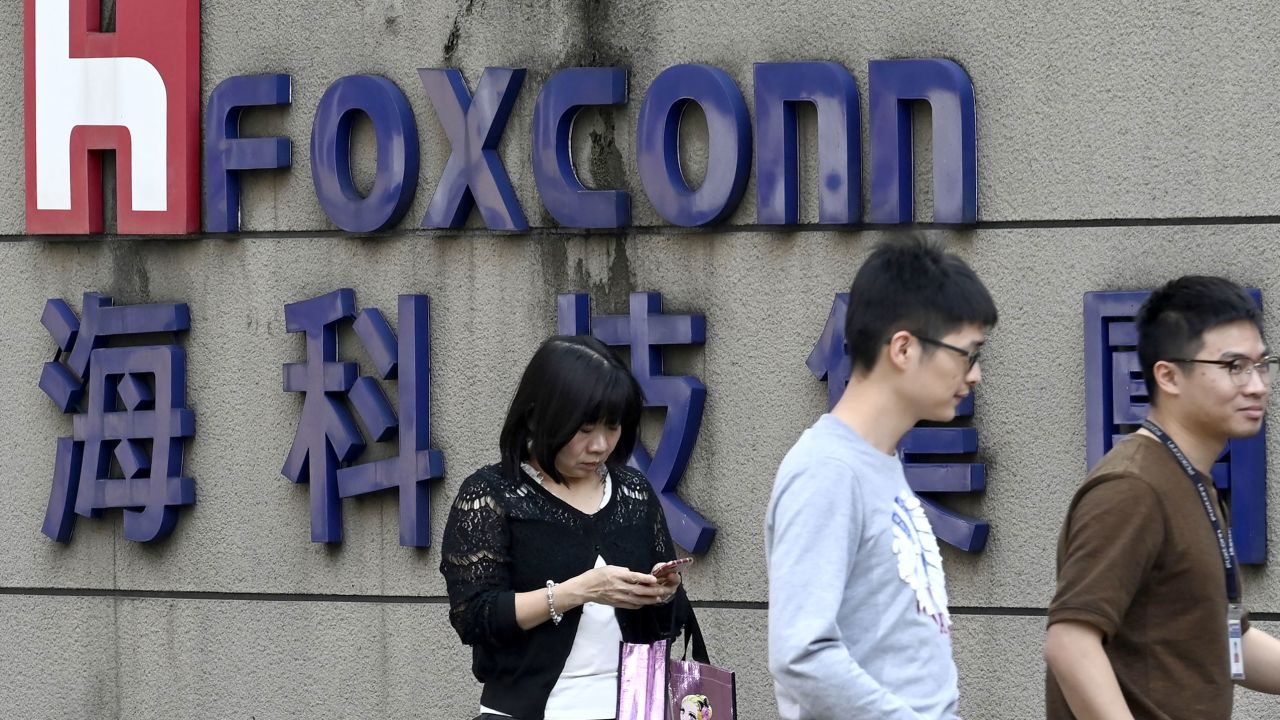 People walking past a Foxconn logo in Taipei.