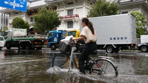 A woman cycles through a flooded area in Tokyo on September 9, 2019.