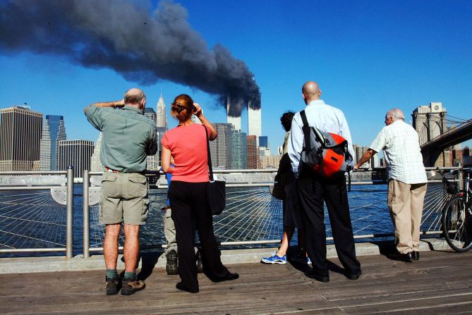 Pedestrians look across the East River to the burning towers.