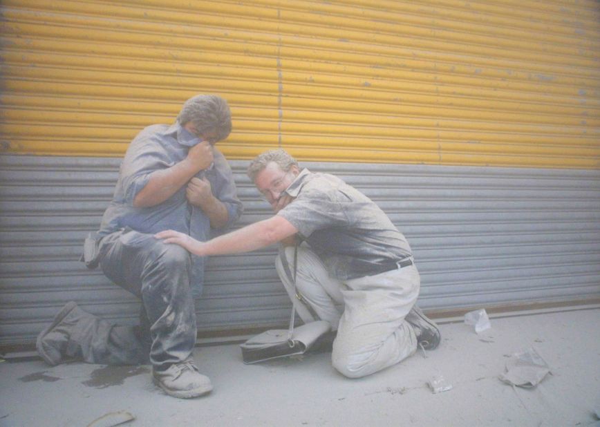 Two men take cover as a dust cloud from the collapsed building envelops lower Manhattan.