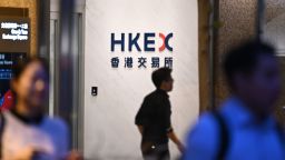 People are seen walking pass a logo of the Hong Kong Stock Exchange in Hong Kong on September 11, 2019. Hong Kong Stock Exchanges and Clearing (HKEX) announced today that HKEX has offered to buy the London Stock Exchange for US $36.6 Billion.