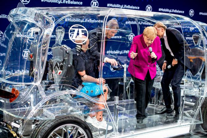 German Chancellor Angela Merkel climbs out of a transparent car during an auto show in Frankfurt, Germany, on Thursday, September 12.