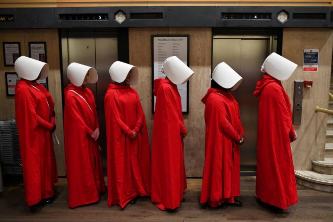 People dressed up as characters from Margaret Atwood's "The Handmaid's Tale" line up at a bookstore in London to get a copy of her new novel, "The Testaments," on Monday, September 9.