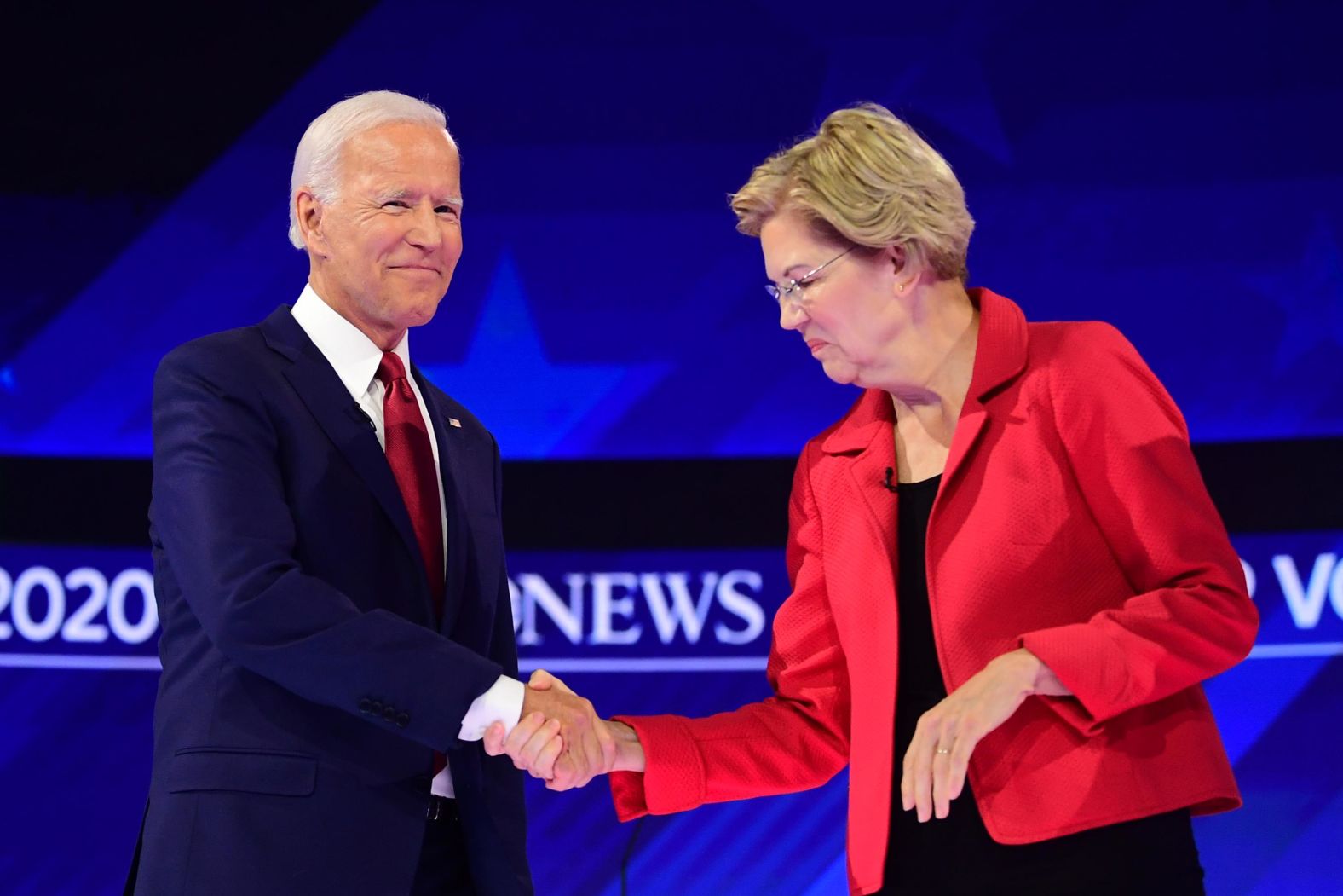 Biden and Warren shake hands as they arrive on stage.