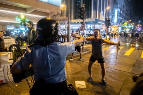 A police officer aims a gun in front of a protester on August 25.