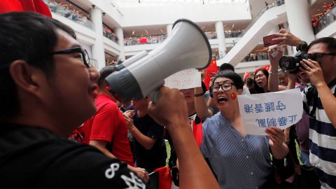 Pro-government and anti-government supporters chant against one another at a shopping mall in Hong Kong on Friday, September 13. The sign translates to 