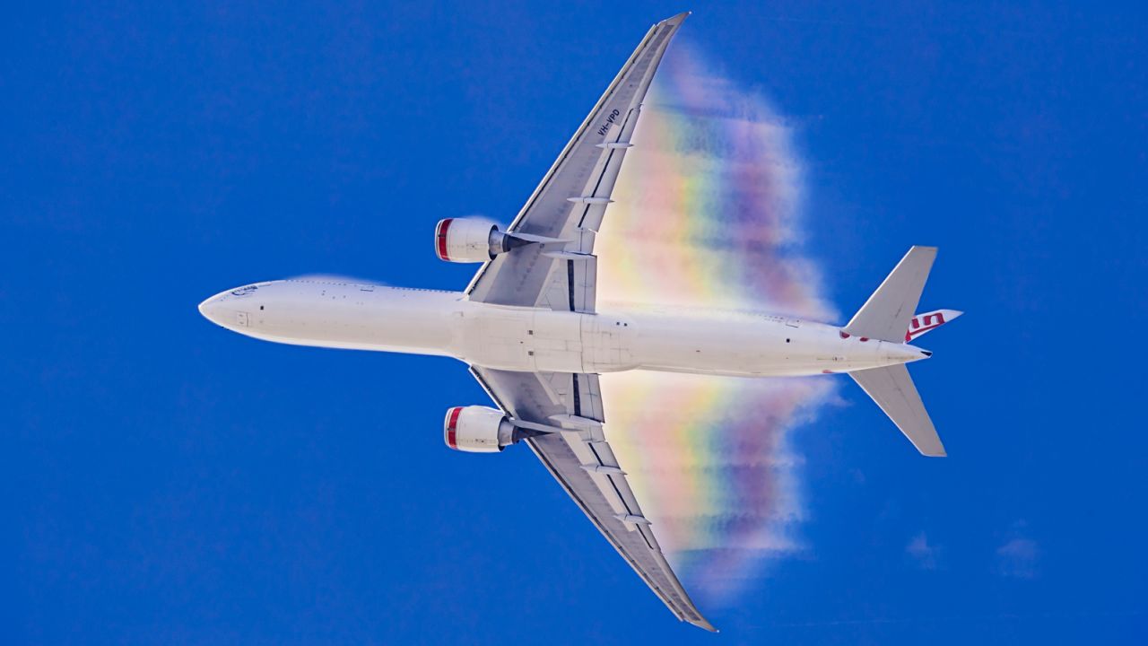 A Virgin Australia Boeing 777 with a condensation rainbow stretching out behind.