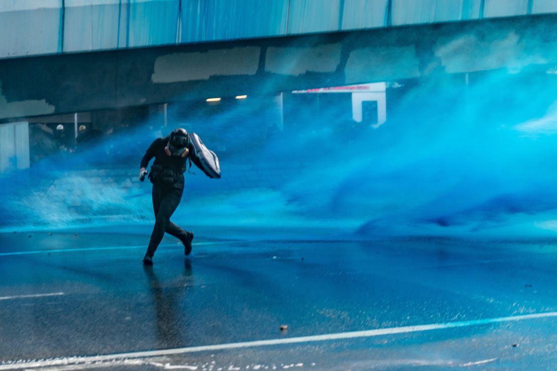Pro-democracy protesters react as police fire water cannons at them outside the Central Government Complex on September 15, 2019 in Hong Kong.