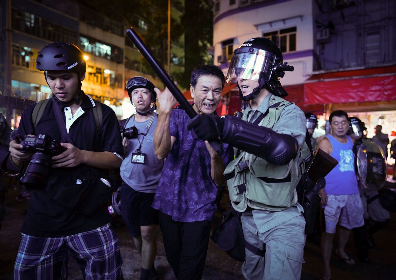 A pro-China supporter, center, is escorted by police after confronting journalists in Hong Kong on September 15.