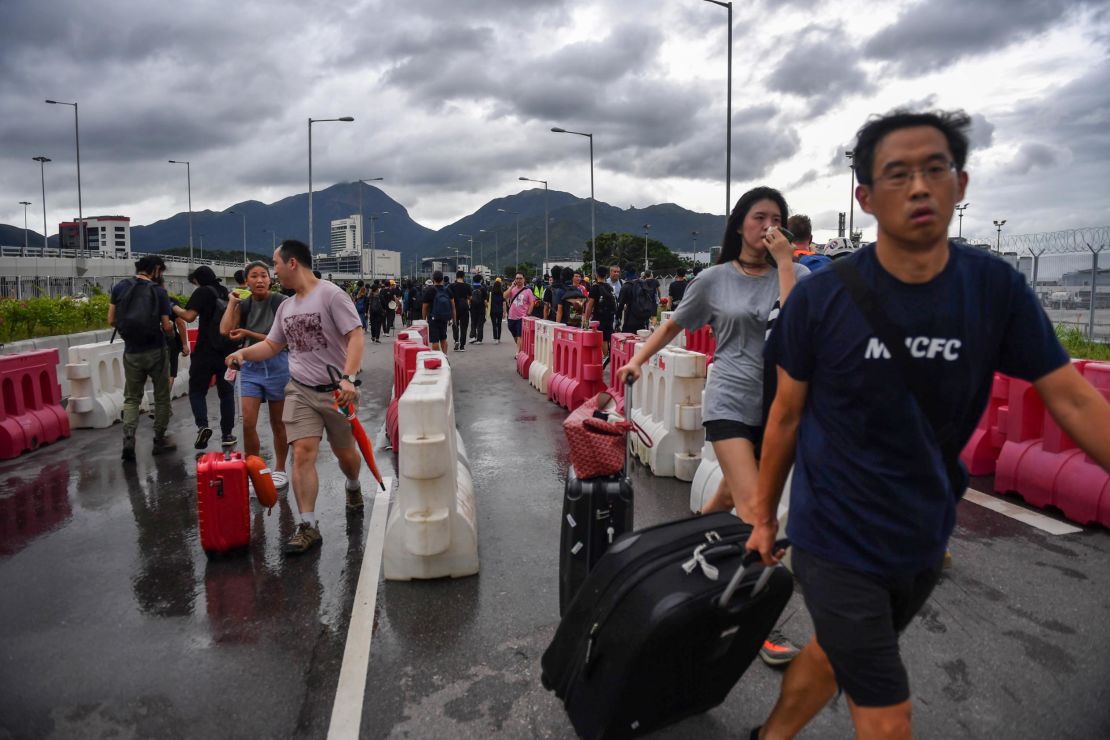 Passengers walk through barriers set up by protesters on a road near Hong Kong International Airport on September 1, 2019.